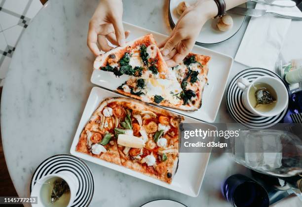 top shot of hands holding and enjoying freshly made pizza slices in the restaurant - dining overlooking water stock pictures, royalty-free photos & images