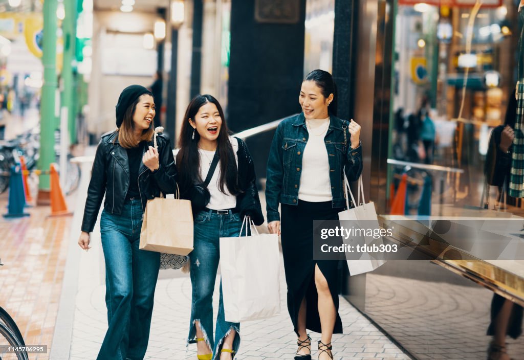 Tres mujeres adultas medianas con bolsas de compras en la ciudad