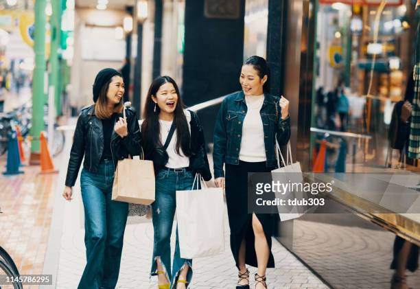 three mid adult women with bags shopping in the city - shopping asia stock pictures, royalty-free photos & images