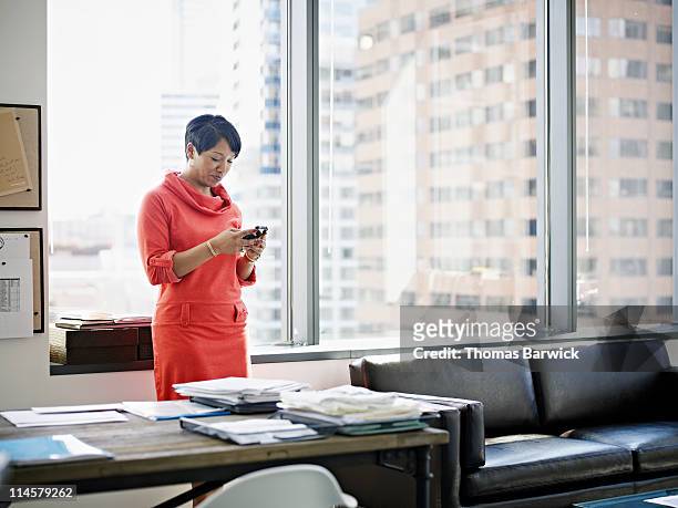 businesswoman standing looking at smart phone - minority groups professional stock pictures, royalty-free photos & images