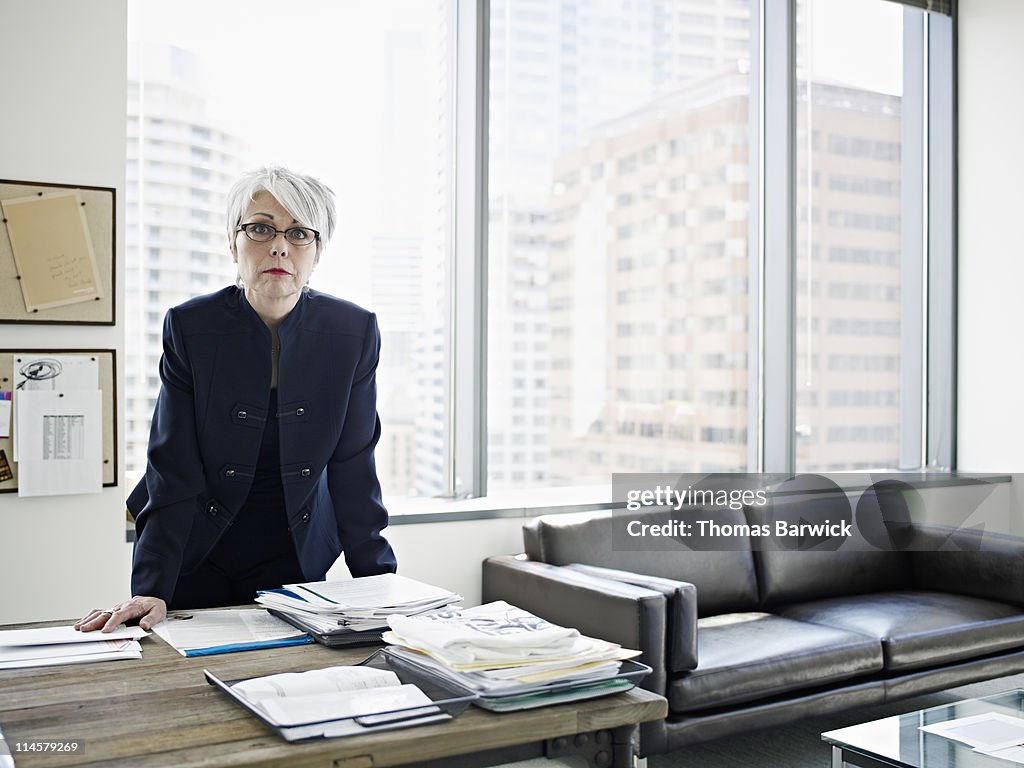 Businesswoman standing with hands resting on desk