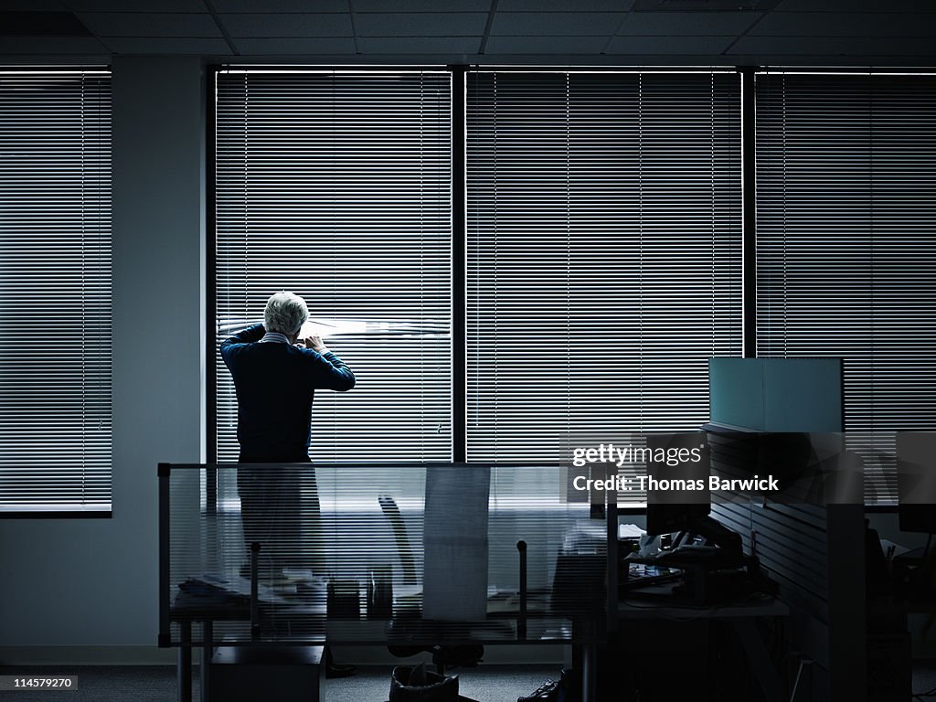 Businessman looking through closed blinds