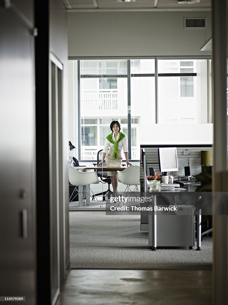 Businesswoman standing in office hands on desk