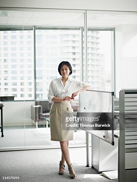 businesswoman in office arm resting on workstation - woman leaning stock pictures, royalty-free photos & images