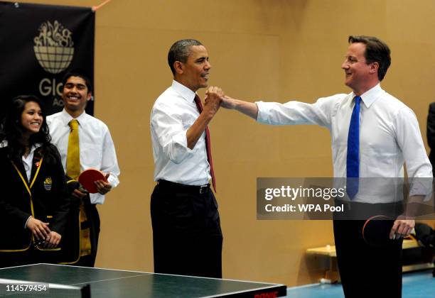 President Barack Obama and Britain's Prime Minister David Cameron high-five as they play table tennis at Globe Academy on May 24, 2011 in London,...