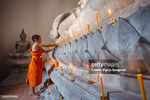 young monk worship the buddha with candle and light at wat phutthai sawan - portrait zen stock pictures, royalty-free photos & images