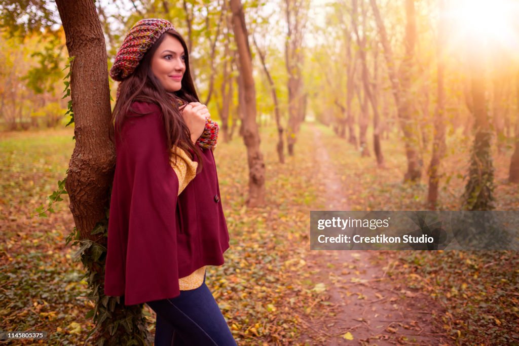 Beautiful girl in stylish fall fashion clothes in park scenery, in nice warm autumn sunlight. Gorgeous romantic young woman outdoors. American plan shot in natural light, retouched, vibrant colors