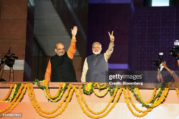Amit Shah, president of the Bhartiya Janata Party , left, and Narendra Modi, India's prime minister, gesture to the crowd during an event at the...