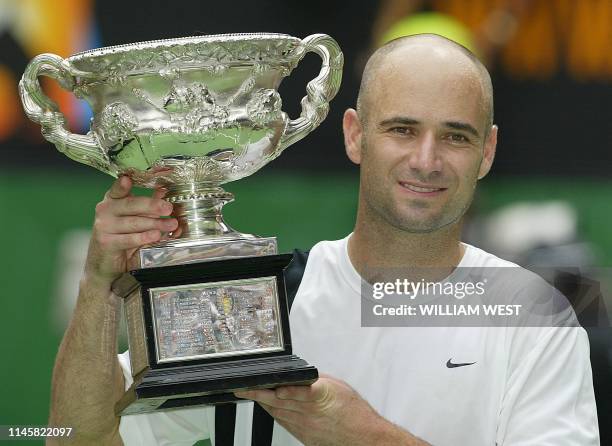 Andre Agassi of the US poses with the winner's trophy following his victory over Rainer Schuettler of Germany in the men's singles final at the...