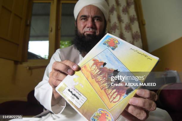 Mohammad Iltimas, a Pakistani former religious teacher of "American Taliban" John Walker Lindh, displays a school book of Lindh at his residence in...