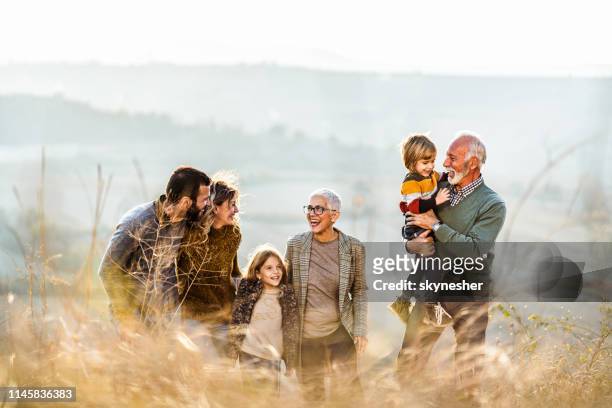 happy extended familie communiceren tijdens het wandelen in de herfst dag op een heuvel. - multi generation family stockfoto's en -beelden