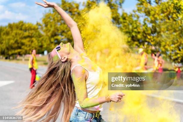 carefree woman dancing in powder on the holi festival - colour powder explosion stock pictures, royalty-free photos & images