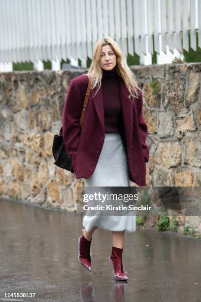 Fashion Consultant Creative Director and Founder of Midnight 00 Ada Kokosar wears Midnight 00 shoes, Loewe bag, a burgundy wool coat, burgundy roll...