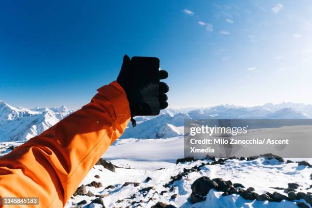 mountaineer takes selfie on summit - トレーニンググローブ ストックフォトと画像