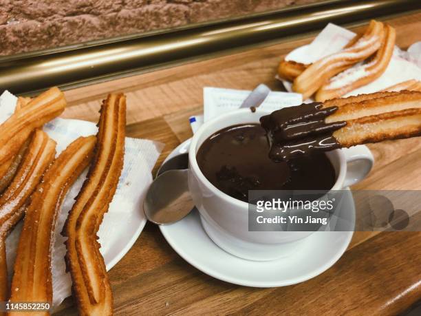 close-up view of spanish churros and hot chocolate served on wooden table - churros stock pictures, royalty-free photos & images
