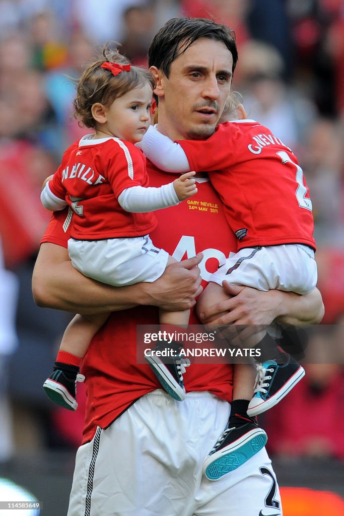 Manchester United's English defender Gary Neville carries children