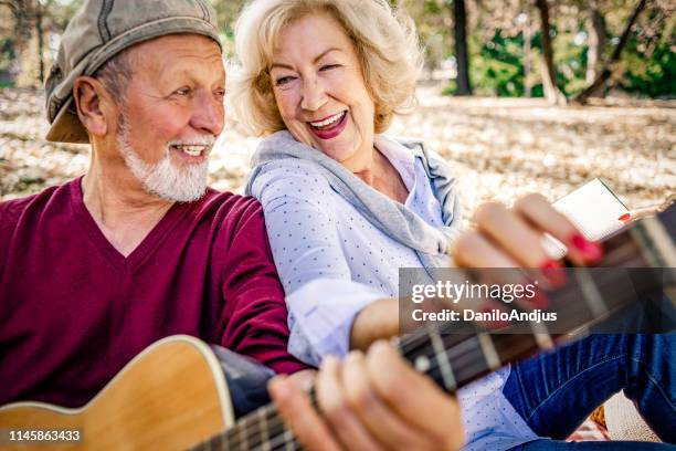 cheerful senior couple enjoying picnic together - guitar & medical books stock pictures, royalty-free photos & images