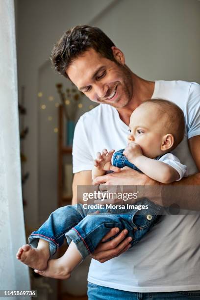 smiling handsome father carrying cute son at home - dad and baby stock pictures, royalty-free photos & images