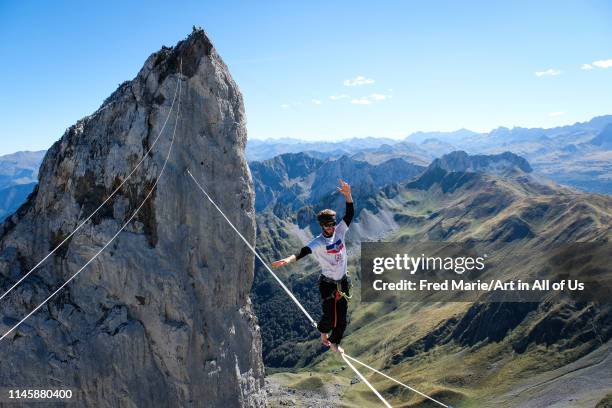 Man walking on a highline in the french pyrenees with his friend on the top of a cliff, Nouvelle-aquitaine, Lescun, France on March 19, 2018 in...