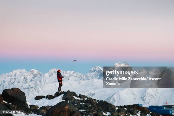 mountaineer flies drone towards mountain summit - drone flying ストックフォトと画像