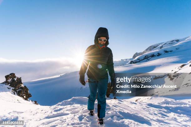 mountaineer walks towards the camera in the morning light - ski pants stockfoto's en -beelden