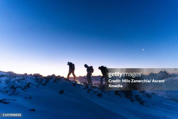 mountaineers advance towards mountain summit in the twilight - people climbing walking mountain group stock pictures, royalty-free photos & images