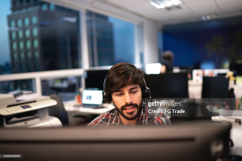 Empregado que trabalha com auriculares no callcenter do escritório