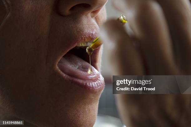 woman taking cannabis drops - cbd oil stock pictures, royalty-free photos & images