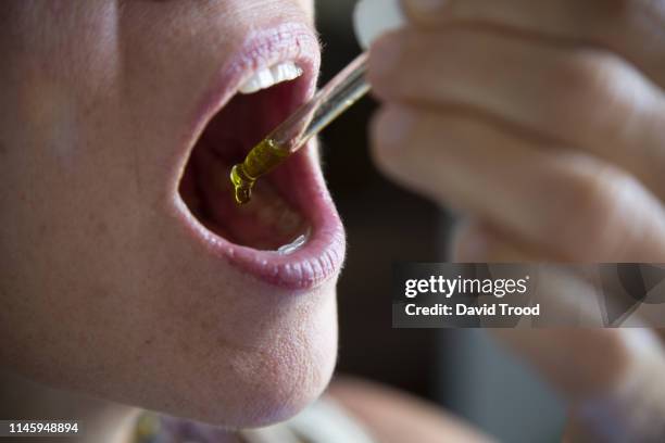 woman taking cannabis drops - cannabidiol stock-fotos und bilder