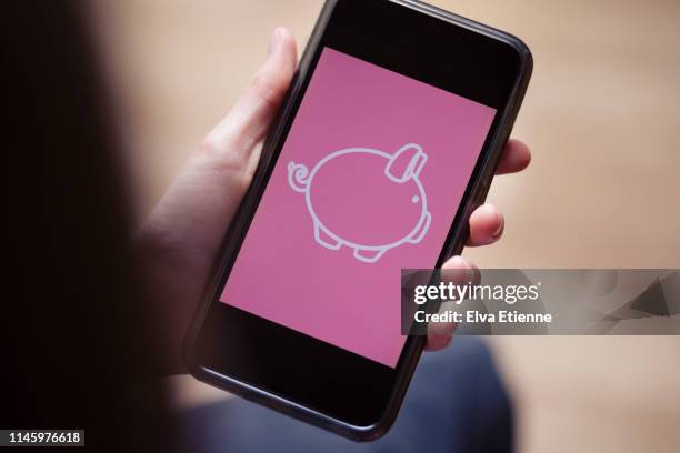 teenager holding mobile phone with conceptual digital piggy bank on screen - internet banking stock pictures, royalty-free photos & images