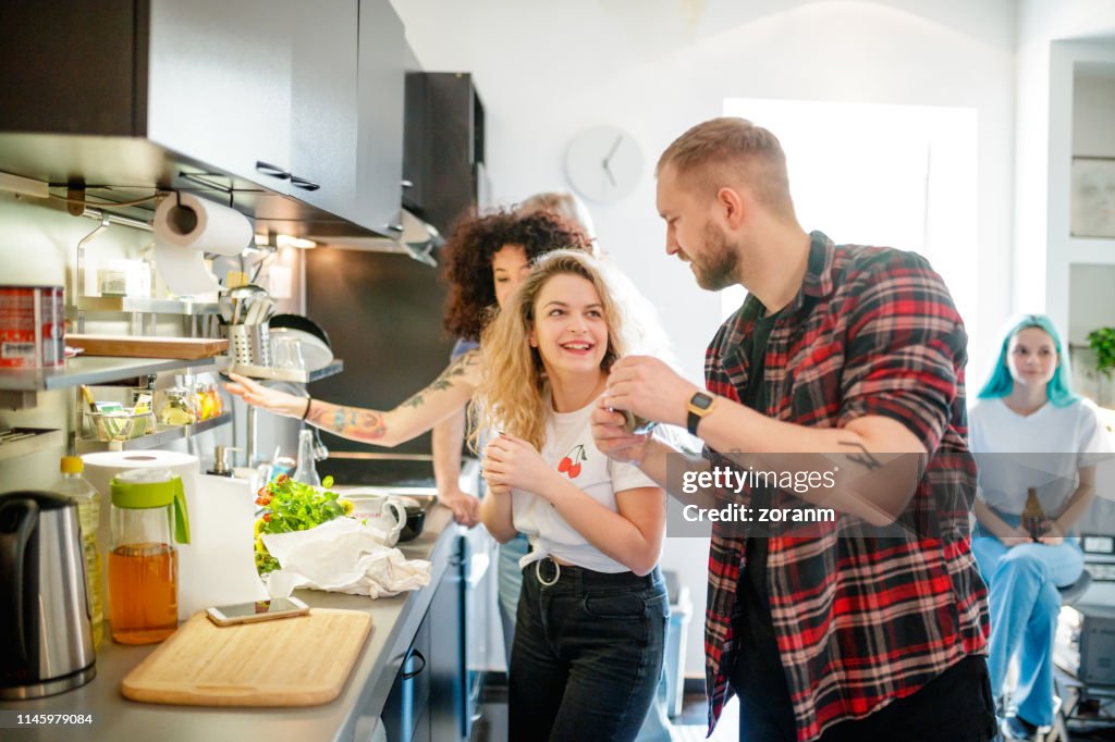 Vrolijke jonge Flatmates met vrienden in de keuken