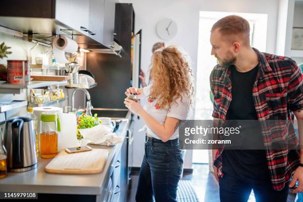 woman in the kitchen trying to open spice jar, flatmate looking at her - jars kitchen stock pictures, royalty-free photos & images