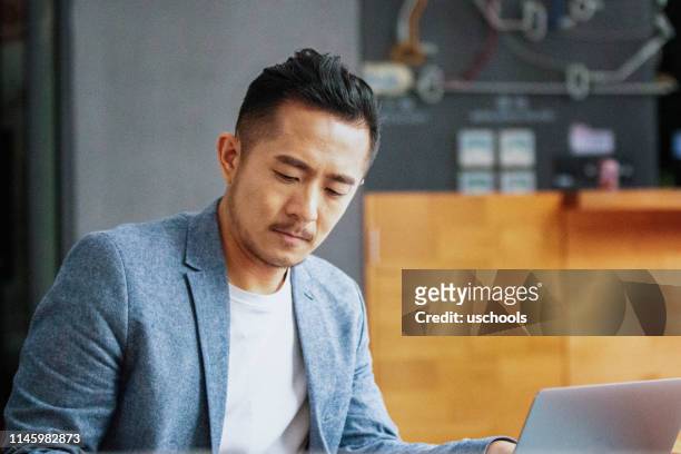 junger asiatischer unternehmer nutzt laptop im modernen bürokorridor - central asia stock-fotos und bilder