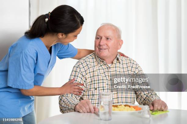 home caregiver giving senior man lunch - aged care food stock pictures, royalty-free photos & images