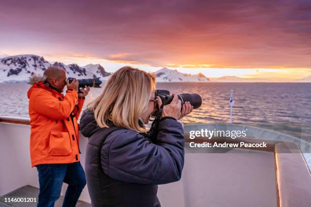 a man and woman photographing sunset in antarctica - antarctica people stock pictures, royalty-free photos & images