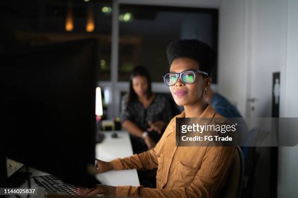 ritratto di imprenditrice che lavora fino a tardi in ufficio - persona in secondo piano foto e immagini stock