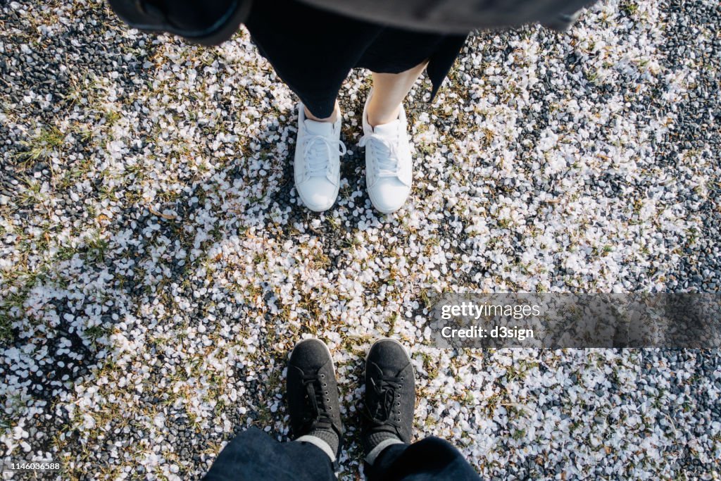 Subject view of the low section of a loving couple on gravel path with fallen cherry blossom petals