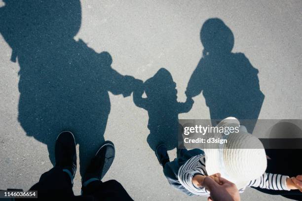 shadow on gravel path of a loving family of three holding hands walking outdoors on a lovely sunny day - 家族　シルエット ストックフォトと画像