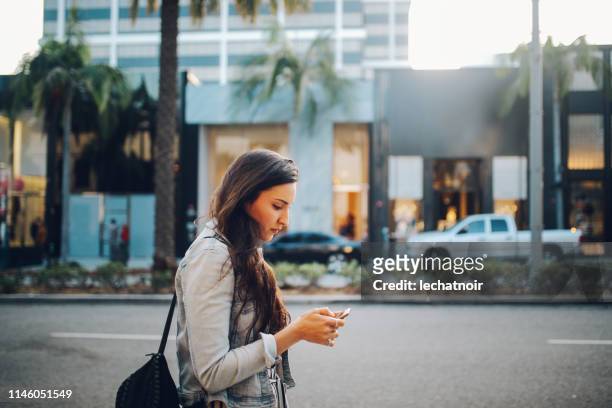 young woman in los angeles, trying to find a rideshare service - beverly hills ca stock pictures, royalty-free photos & images