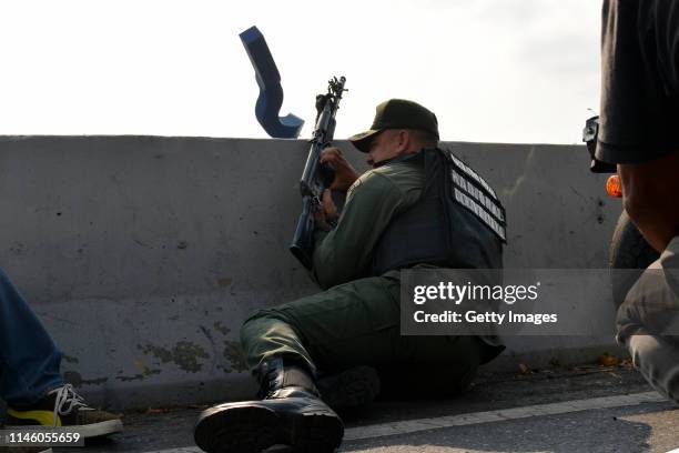 Pro-Guaidó soldier protects himself behind a wall as he hold a machine gun outside the air force base La Carlota on April 30, 2019 in Caracas,...