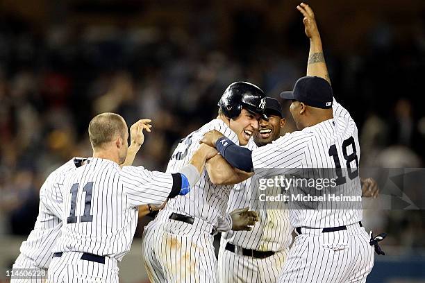 Mark Teixeira of the New York Yankees celebrates with Brett Gardner and Andruw Jones after hitting a game winning RBI in the ninth inning against the...