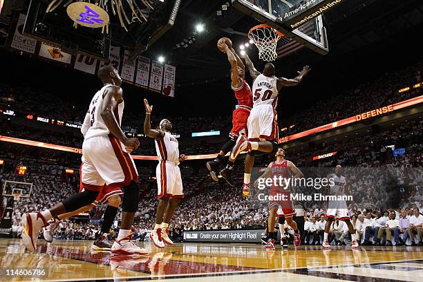 Derrick Rose of the Chicago Bulls dunks on Joel Anthony of the Miami Heat as LeBron James of the Heat looks on in the first half of Game Four of the...