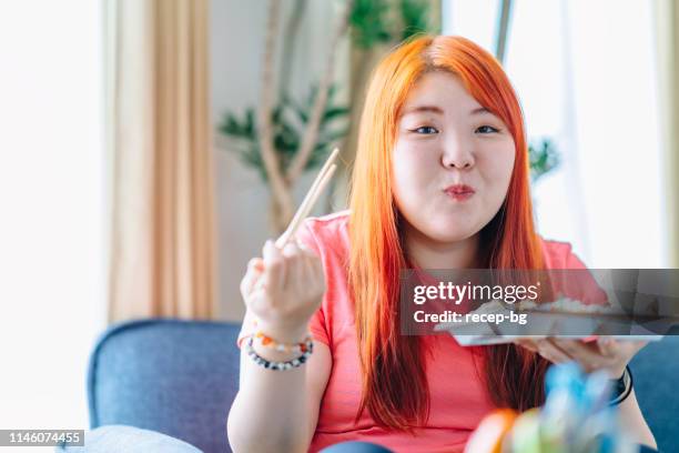 junge frau isst zu hause mittagessen - fat asian woman stock-fotos und bilder