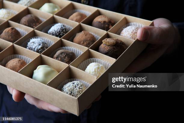 box of chocolates in male hands on a dark background - chocolate box stock-fotos und bilder