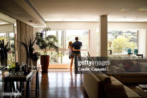 Pareja admirando la vista desde la sala de estar de su casa. Pareja admirando la vista desde la sala de estar de su casa.