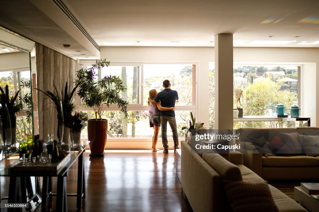 Paar bewonderen het uitzicht vanuit de woonkamer van hun huis.