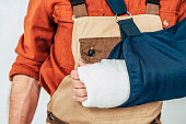 cropped view of repairman with broken arm and bandage on white background