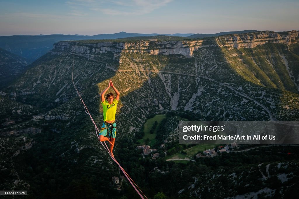 A man walking on the longest slackline ever in navacelles circus (world humanity patrimony) at 300 meters high, Occitanie, Navacelles, France...