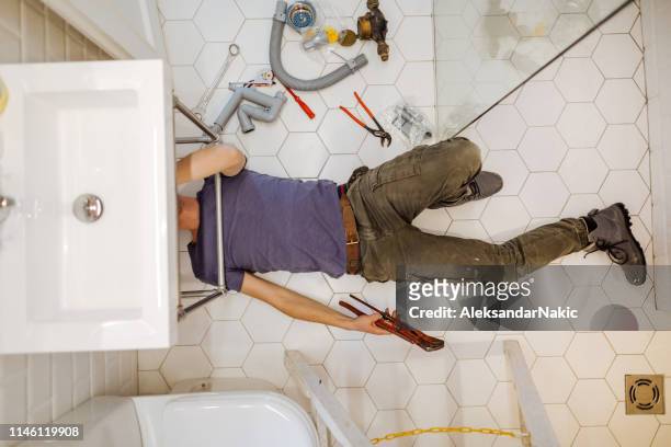 uomo che risolve problemi idraulici nel suo bagno - under sink foto e immagini stock