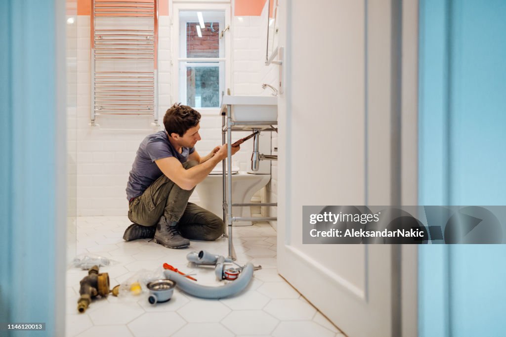 Young man fixing a leak under the bathroom sink